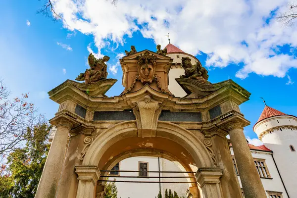 Tarihi Avrupa kalesinde mavi gökyüzüne karşı heykellerle süslü taş kemer yolu. 17 Mart 2025, Konopiste Şatosu, Çek Cumhuriyeti.