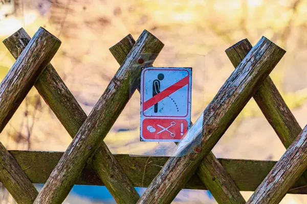 Açık hava parkı ortamında ahşap çitlerde umumi çiş işareti yok. 18 Mart 2025, Madalyon, Çek Cumhuriyeti.