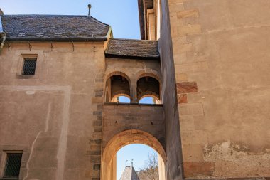 Ortaçağ taş kemer yolu ve açık mavi gökyüzü altındaki binalar.