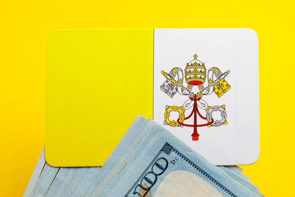 Флаг Ватикана с долларовыми купюрами на желтом фоне.