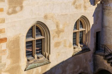 Gotik kemerli pencereleri ve demir ızgaraları olan tarihi taş bina..
