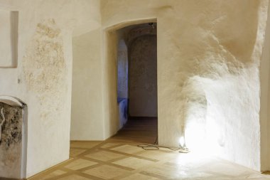 Işıklı, dokulu duvarları ve kemerli kapı aralığı olan tarihi taş koridor..