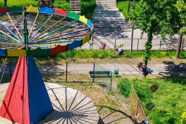 Güneşli parkta yeşil ve patikalı renkli boş bir salıncak..