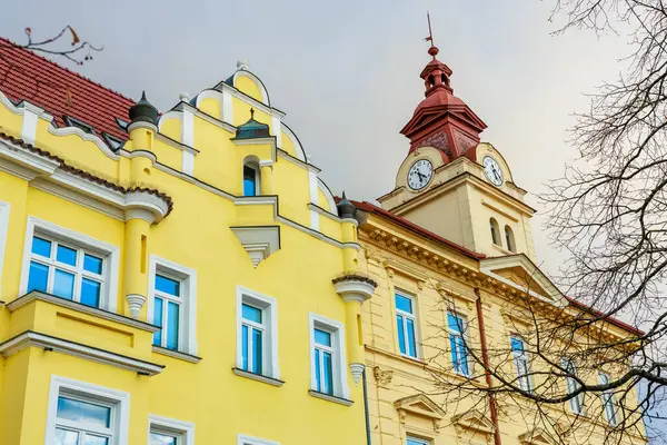 Parlak sarı cepheli ve saat kulesi mimarili tarihi Avrupa binaları.