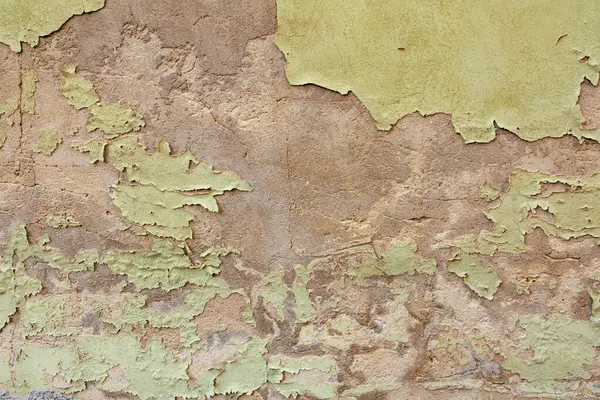 Bej ve yeşil katmanlı desenli duvar yüzeyinin soyulması.
