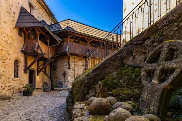 Kırsal ahşap mimarisi ve yosun aksanıyla ortaçağ taş kale avlusu.