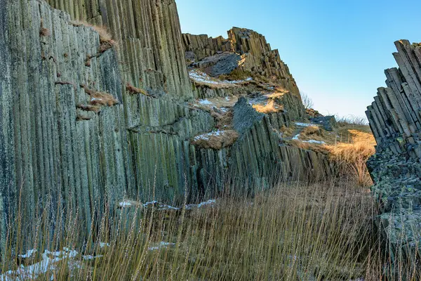 Engebeli arazide berrak mavi gökyüzünün altında görkemli bazalt kaya oluşumları.