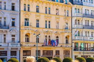 Karlovy 'de bayraklı tarihi astoria oteli cephesi zarif mimari yapılara sahiptir. 19 Mart 2025, Karlovy Vary, Çek Cumhuriyeti.