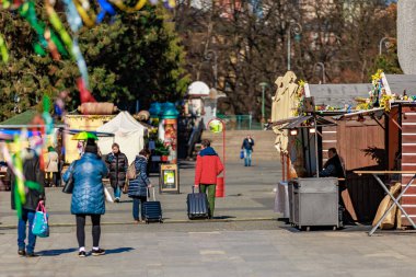 Güneşli bir günde insanların gezip bavullarını taşıdığı açık hava pazarı. 19 Mart 2025, Karlovy Vary, Çek Cumhuriyeti.