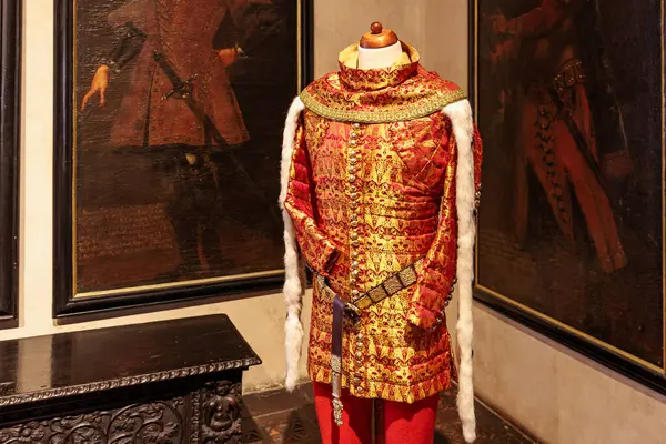 Karanlık odada duvarlarda klasik portrelerle süslenmiş tarihi bir kostüm. 19 Mart 2025, Karlstejn, Çek Cumhuriyeti.