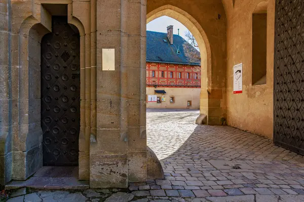 Taş kemer yolu ve kaldırım taşı avlusu olan tarihi mimari. 19 Mart 2025, Karlstejn, Çek Cumhuriyeti.