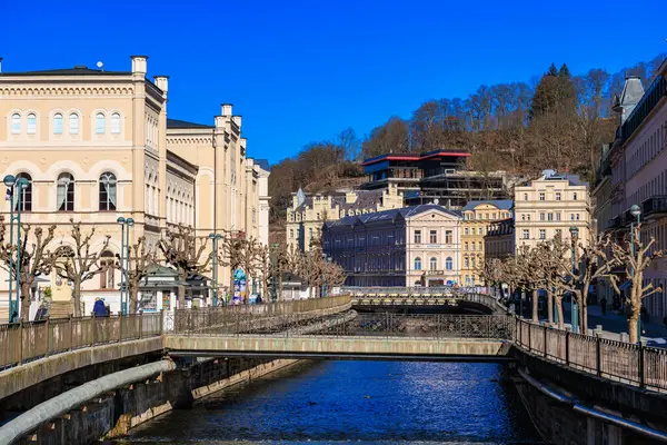 Köprü ile nehir kenarındaki tarihi Avrupa mimarisinin manzarası. 19 Mart 2025, Karlovy Vary, Çek Cumhuriyeti.