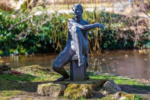 Park ortamında oturan bronz kadın heykeli. 19 Mart 2025, Karlovy Vary, Çek Cumhuriyeti.