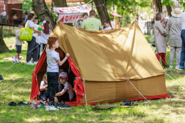 Çocuklar arka planda pankartıyla açık hava festivalinde çadırda oynuyorlar. 22 Mayıs 2025 Balti Moldova.