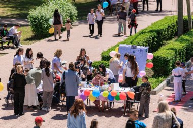 Beyaz tenli yetişkinlerin ve çocukların sanat ve zanaatla meşgul olduğu açık hava etkinliği. 22 Mayıs 2025 Balti Moldova.