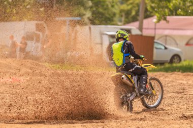 Toprak yolda neon teçhizatlı bir erkek motosikletçi. 31 Mayıs 2025 Vadul lui Voda Moldova.