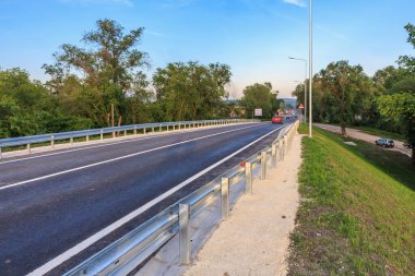 Açık bir günde etrafı yemyeşil ağaçlarla çevrili bariyerlerle dolu boş bir otoyol. 2 Haziran 2025 Balti Moldova.