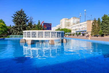 Şehir parkında güneşli bir gün. Mavi çeşmeli ve modern binalı. 5 Haziran 2025 Balti Moldova.