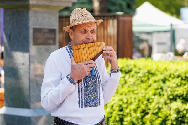 Geleneksel kıyafetlerle dışarıda pan flütü çalan yaşlı beyaz bir erkek. 22 Mayıs 2025 Balti Moldova.