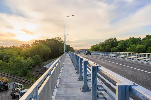 Otoyol köprüsünün üzerinde gün batımında araçlar ve yemyeşil ağaçlar. 2 Haziran 2025 Balti Moldova.