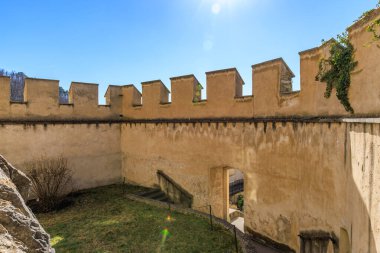 Açık mavi gökyüzünün altında, güneşli siperleri olan tarihi taş kale duvarı..