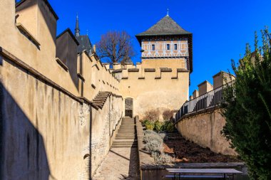 Taş duvarları ve açık mavi gökyüzünün altındaki basamakları olan ortaçağ kale kulesi..