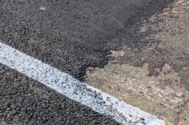 Yol yüzeyinde beyaz çizgi olan asfalt dokusuna yakın çekim.