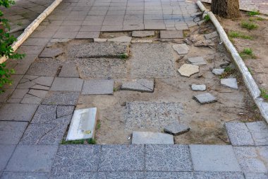 Kırık kiremitleri ve toprak parçalarıyla hasar görmüş şehir kaldırımı.