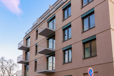 Mavi gökyüzüne karşı balkonları olan modern bir apartman..