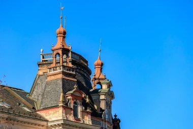 Açık mavi gökyüzü altında taretleri olan Viktorya dönemi mimarisi.