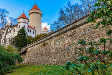 Taş duvarları ve yeşil manzarayla çevrili kırmızı çatı kuleleri olan tarihi Czech kalesi..