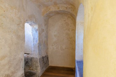 Antik taş ve alçı odası, kemerli kapılar ve ahşap zemin..