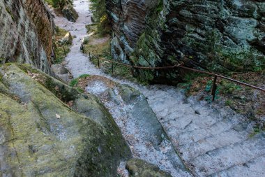 Kayalık kanyondan geçen taş merdiven yosun kaplı kayalar ve parmaklıklarla.