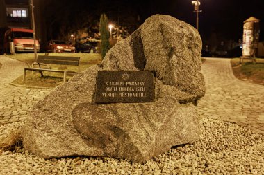 Gece parkı düzeninde tanımlayıcı plaketli soykırım anıtı taşı. 14 Mart 2025, Votice, Çek Cumhuriyeti.