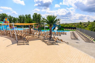 Havuzu ve bir sürü şezlongu olan bir plaj. Sandalyeler yayılmış ve bazıları boş. 8 Haziran 2024 Balti Moldova