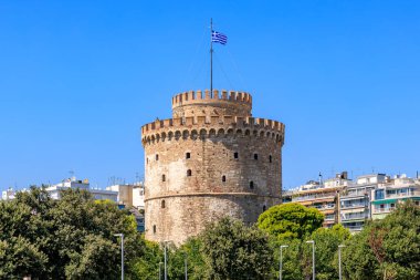 Üzerinde mavi ve beyaz bayrak olan uzun bir kule. Gökyüzü açık ve mavi. Kule ağaçlar ve binalarla çevrilidir. 8 Ağustos 2024 Selanik Yunanistan