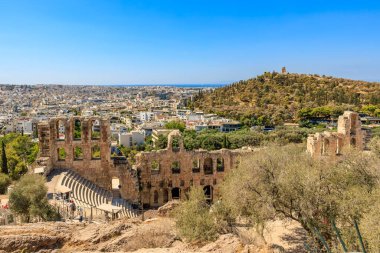 Arkasında büyük bir bina olan bir şehir manzarası. Şehir insanlarla dolu ve gökyüzü açık. 9 Ağustos 2024 Atina Yunanistan