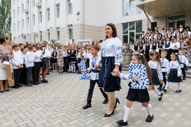 Geleneksel elbiseli beyaz kadın öğretmen ve çocuklarla okul kutlaması. 2 Eylül 2024 Balti Moldova.