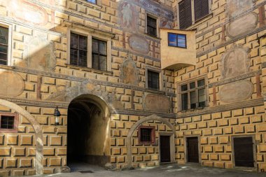 Detaylı freskleri ve kemerli girişi olan tarihi Rönesans avlusu. 20 Mart 2025, Cesky Krumlov, Çek.