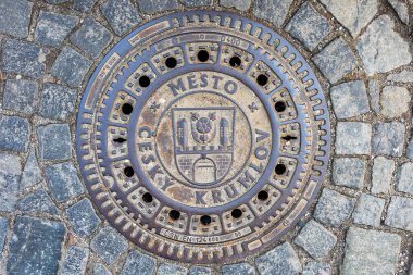 Cesky Krumlov 'un kaldırım taşı sokağındaki rögar kapağı. 20 Mart 2025, Cesky Krumlov, Çek.