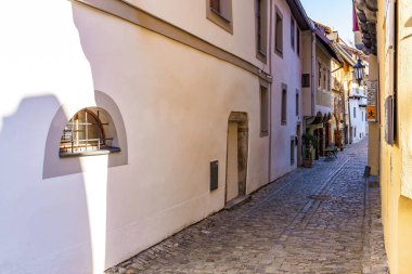 Avrupa 'nın tarihi bir şehrinde güneşli duvarları olan sessiz bir kaldırım taşı sokağı. 20 Mart 2025, Cesky Krumlov, Çek.