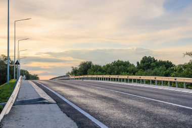 Gün batımında yemyeşil ve dramatik gökyüzü olan boş bir otoyol..