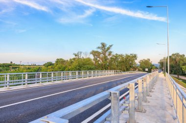 Metal parmaklıkları ve kırsal alanda mavi gökyüzü olan boş otoyol köprüsü.