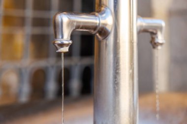 Bulanık arkaplana damlayan metal su pınarlarının yakın çekimi.