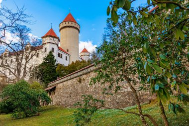 İlkbaharda yemyeşil yeşilliklerle çevrili kırmızı kuleleri ve taş duvarları olan ortaçağ kalesi..