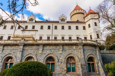 Mavi gökyüzünün altında taş cepheli ve kırmızı taretleri olan tarihi Avrupa kalesi.