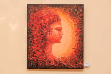 Kırmızı arka planda bir kadının yüzü resmedilir. Kadının yüzü çiçeklerle çevrili ve arkası turuncu. 12 Mart 2024 Balti Moldova