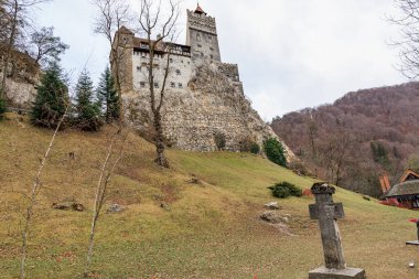 Kale, elinde haç ve mezar taşı olan bir tepede. 16 Aralık 2024 Bran Romanya.