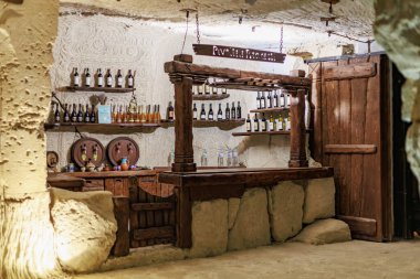 Kırsal şarap mahzeni, ahşap bar ve mağara düzeninde taş duvarlar. 6 Nisan 2025 Branesti, Moldova.