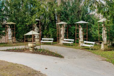 Klasik heykelleri ve yapraklı bankları olan sakin bir bahçe. 17 Mart 2025, Konopiste Şatosu, Çek Cumhuriyeti.